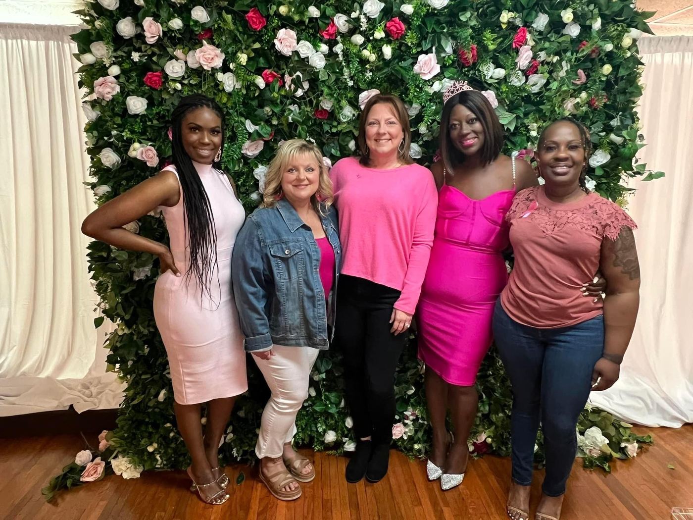 Group of five survivors posing at the floral wall